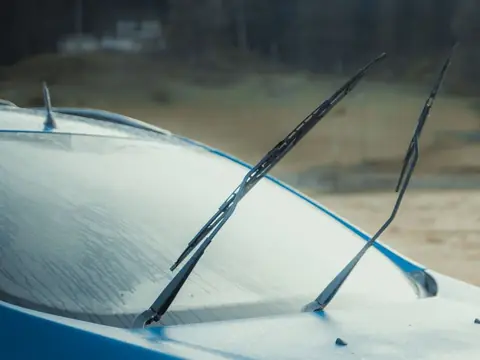 Wipers lifted off the frosted windshield of a blue SUV