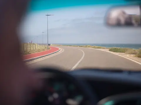 The road ahead seen through a car windshield past the rear view mirror